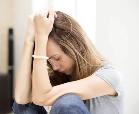 Woman sitting on floor with head in her hands looking upset and distraught. Anxiety treatment in Powhatan, VA can help you. Meet with an online therapist in Virginia to get support! 