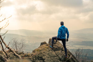 Image of a happy triumphant man on a hike looking at the landscape after having depression treatment in richmond, va through onlin counseling and therapy. 23173