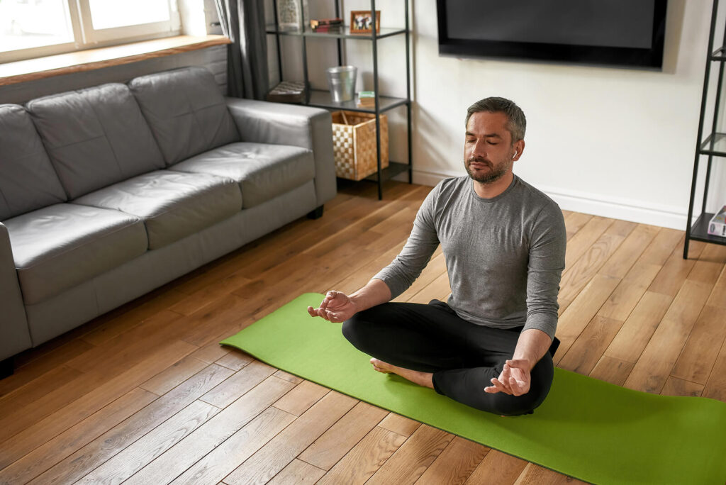 Man doing yoga on the floor in his home. Mindfulness-based therapy in Virginia can help with anxiety, depression, trauma and more. Reach out for mindfulness therapy via online therapy in Virginia.