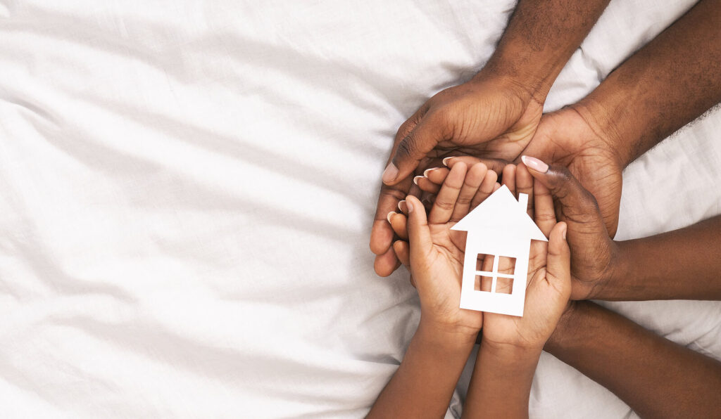 Family with hands together with a paper house resting on their palms representing healed family relationships. Healing from childhood trauma is possible with trauma therapy in Virginia. Learn more here.