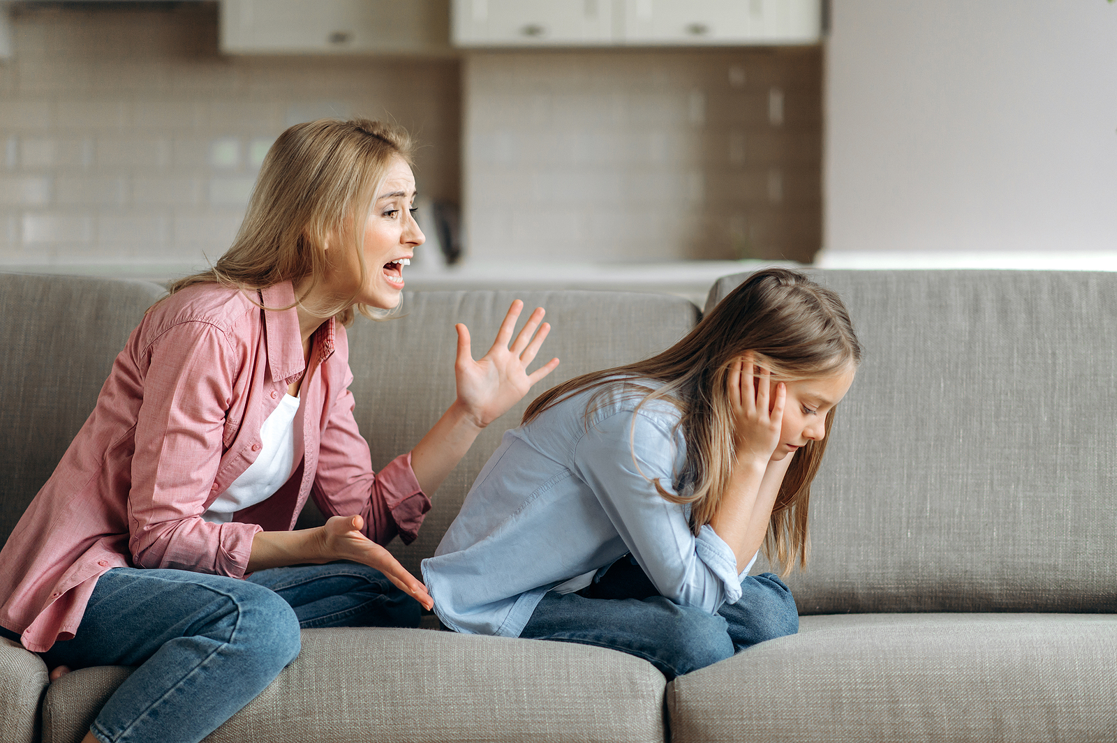 Mom shouting at daughter on the couch as daughter covers her ears. Childhood trauma can impact every aspect of your adult life. Therapy for children of narcissistic parents can help you overcome your past for a brighter future.