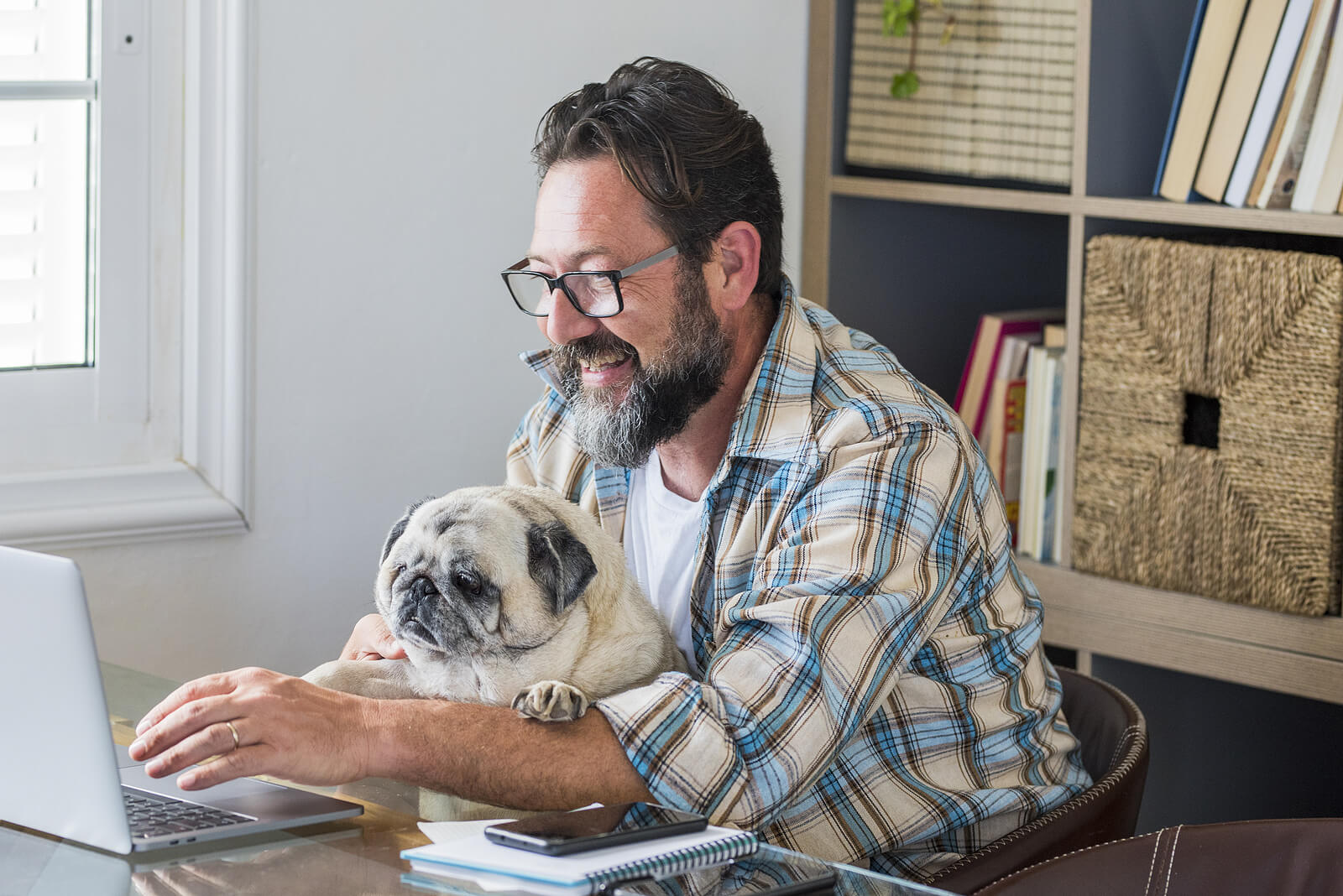 Man holding his dog while sitting at his laptop representing the ease of participating in EMDR Intensives in Virginia. Work through past trauma in the comfort of your own home and conquer your trauma. Learn more here.