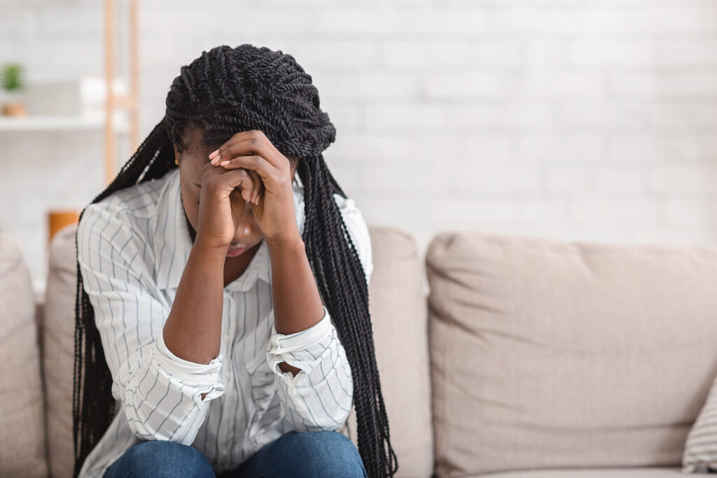 A woman covers her face with her hands, hiding an upset expression. Learn more about therapy for trauma in Richmond, VA and how online therapy in Virginia can offer support from home. 