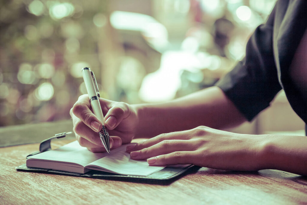 A close-up of a person writing in a journal. This could represent a coping skill learned by working with an equine therapist in Virginia. Learn more about equine therapy in Virginia and the support online therapy in Virginia can offer today. 