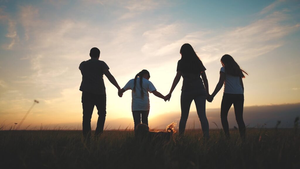 A family fo four walks through a field towards a sunset. Learn how trauma therapy in Richmond, VA can help you better understand past family dynamics. Contact an equine therapist in Virginia for support or search anxiety therapist in Richmond, VA. 