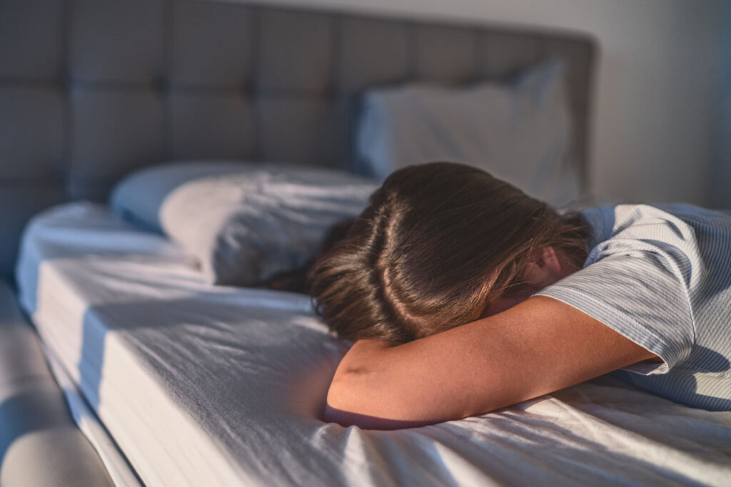 A woman lays her head down in bed in the morning light. This could represent the struggles of depression that depression treatment in Richmond, VA can help you address. Learn more about the help an equine therapist in virginia can offer. 