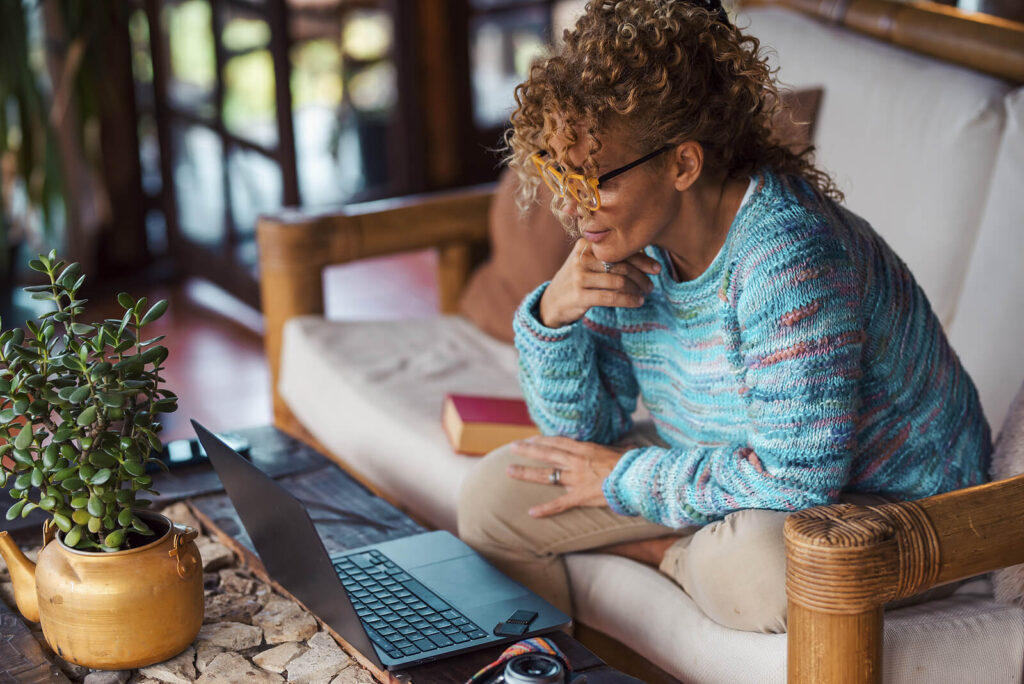 A woman smiles while looking at her laptop. This could represent the ease of access that online therapy in Culpeper, VA can offer. Learn more about online therapy in Virginia by searching for an equine therapist in Virginia today. 