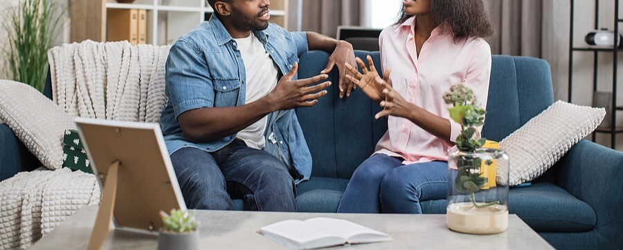 A couple appears to argue while sitting on a sofa together. Learn how life transitions therapy in Charlottesville VA can offer help with stressful conversations. Search for trauma therapy in Richmond, VA and the help a life transitions therapist in Fredericksburg, VA can offer today. 