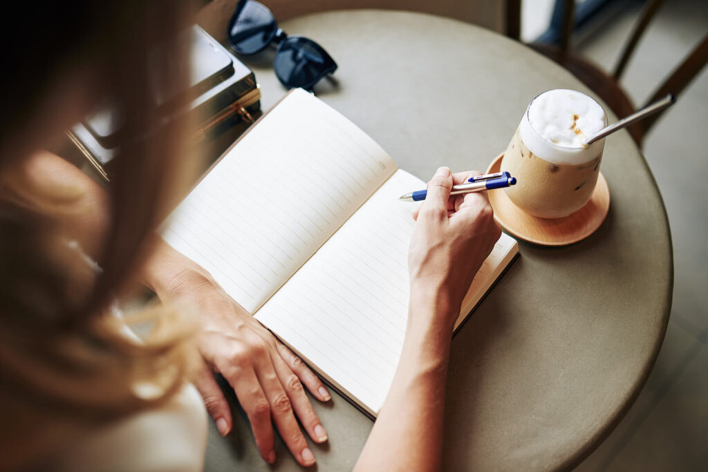 A close up of a person journaling at a desk. A life transitions therapist in Fredericksburg, VA can teach you new coping techniques via online therapy in Virginia. Learn more about therapy for life transitions therapy in Virginia to learn more today. 