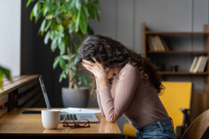 A woman touches both sides of her head while hanging her head over a laptop at her computer desk. Learn how online therapy in Virginia can help you address depression, anxiety, and more! Search for depression treatment in Powhatan, VA and contact an equine sports therapist in Richmond, VA for support. 