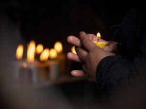 A close up of a person holding a candle. This could represent remembering a passed loved one and how an equine therapist in Virginia can offer support. Search for equine therapy in virginia to learn more about the benefits of equine sports therapy in Richmond, VA. 