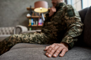 A close up of a man in military clothes sitting on a couch. This could represent the support a therapist for men in lynchburg, va can offer via therapy for trauma in richmond va. Search for equine sports therapy in Virginia and other services for support. 