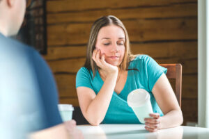 A woman looks at a coffee cup while ignoring the person sitting across from her. This could represent a sign of narcissism that a narcissism therapist in Richmond, VA can help address. Learn more about therapy for self esteem in Virginia and other services today. 