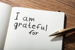 A close-up of an open notebook with the words "I am grateful for" written in black ink, accompanied by a gold pen. Learn how gratitude can help cultivate healthy relationships by contacting a narcissism therapist in Richmond, VA. They can offer narcissism therapy in Richmond, VA and other services. 