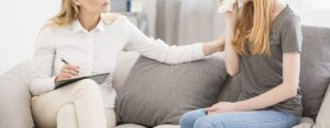 A compassionate therapist comforts a crying teenage girl during a session, illustrating the importance of narcissism therapy in Richmond, VA. This moment captures the healing power of therapy for children of narcissistic parents and highlights the supportive approach of a trauma therapist in Richmond, VA. 