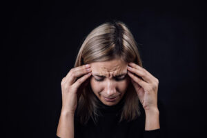A distressed woman holds her head and cries, symbolizing the emotional toll of growing up with a narcissistic parent. This image reflects the deep need for therapy for children of narcissistic parents, particularly with a trauma therapist in Richmond, VA or an online therapist in Powhatan, VA who understands narcissistic abuse recovery. 