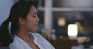 A peaceful woman sitting calmly in a softly lit room with eyes closed, embodying the relief that can come from EMDR therapy in Richmond, VA. This moment of calm is often the goal for those working with a trauma therapist in Richmond, VA or receiving EMDR in Richmond, VA. 