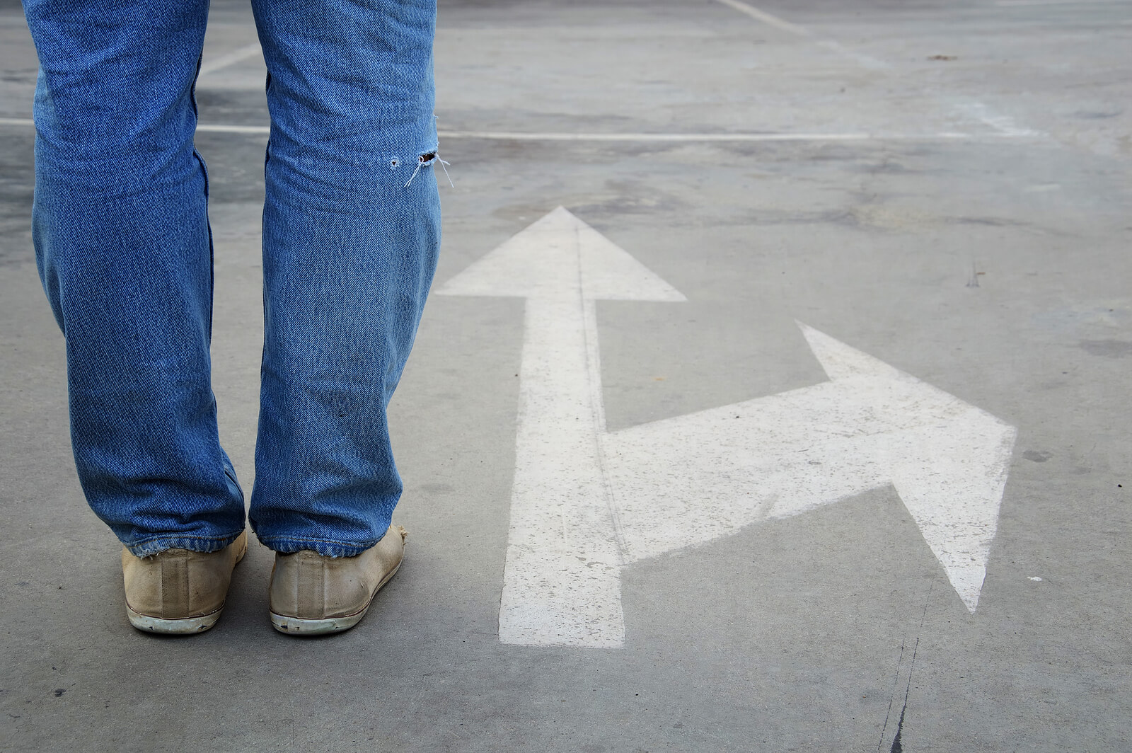 A person stands at a crossroads facing two arrows pointing in different directions, symbolizing uncertainty during major life changes. This image reflects the support offered through therapy for life transitions in Powhatan, VA and life transitions therapy in Virginia. It represents the guidance of a life transition therapist in Powhatan, VA when decisions feel overwhelming.