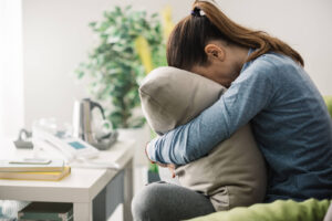 A person sits on a couch hugging a pillow, showing emotional exhaustion and grief often experienced during big life shifts. This moment reflects the kind of support found in therapy for life transitions in Powhatan, VA and life transitions therapy in Lynchburg, VA. Many people turn to therapy for life transitions in Virginia when coping feels heavy and isolating. 