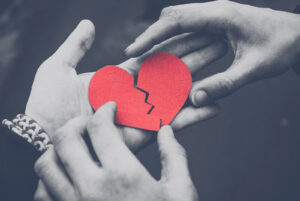 Hands holding a broken paper heart, symbolizing relational pain and repair after trauma. Trauma therapy in richmond, va with a trauma therapist in richmond, va can help rebuild trust, and trauma therapy in charlottesville va may also be a supportive option. 
