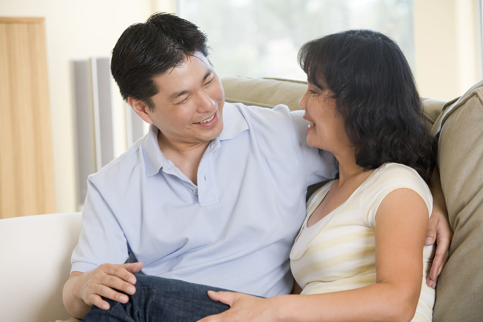 Couple sitting close on a couch and smiling, reflecting connection and safety built through therapy for trauma in richmond va. Support from a trauma therapist in richmond, va can help, and trauma therapy in richmond, va may strengthen attachment.