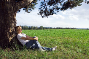 Woman resting peacefully under a tree in an open field, capturing the calm found after intensive EMDR therapy in Powhatan, VA, EMDR intensives in Richmond, VA, and life transitions therapy in Fredericksburg, VA. 