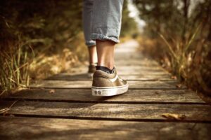 A close-up of someone walking forward along a weathered wooden boardwalk through tall grass, representing the steady, purposeful forward movement that becomes possible after intensive EMDR therapy in Richmond, VA. Whether you're exploring EMDR intensives in Richmond, VA for the first time or returning to deepen previous work, this image captures what it feels like to finally leave the stuck place behind. Intensive therapy in Richmond, VA gives you the momentum to keep walking.
